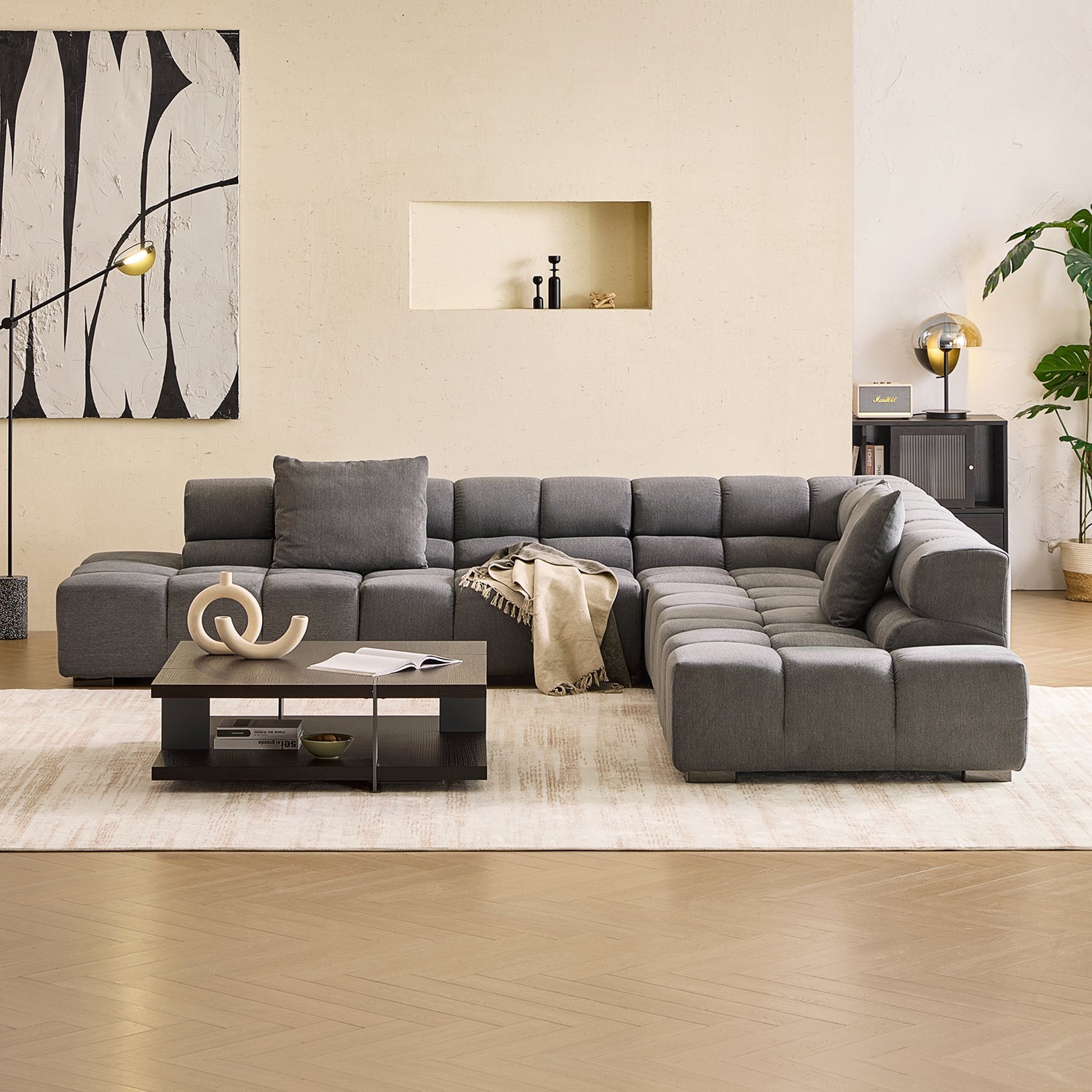 Modern living room with art hanging on one of its beige walls. There is a floor rug, coffee table and a Mario Capasa tufted modular couch in the center of the room.