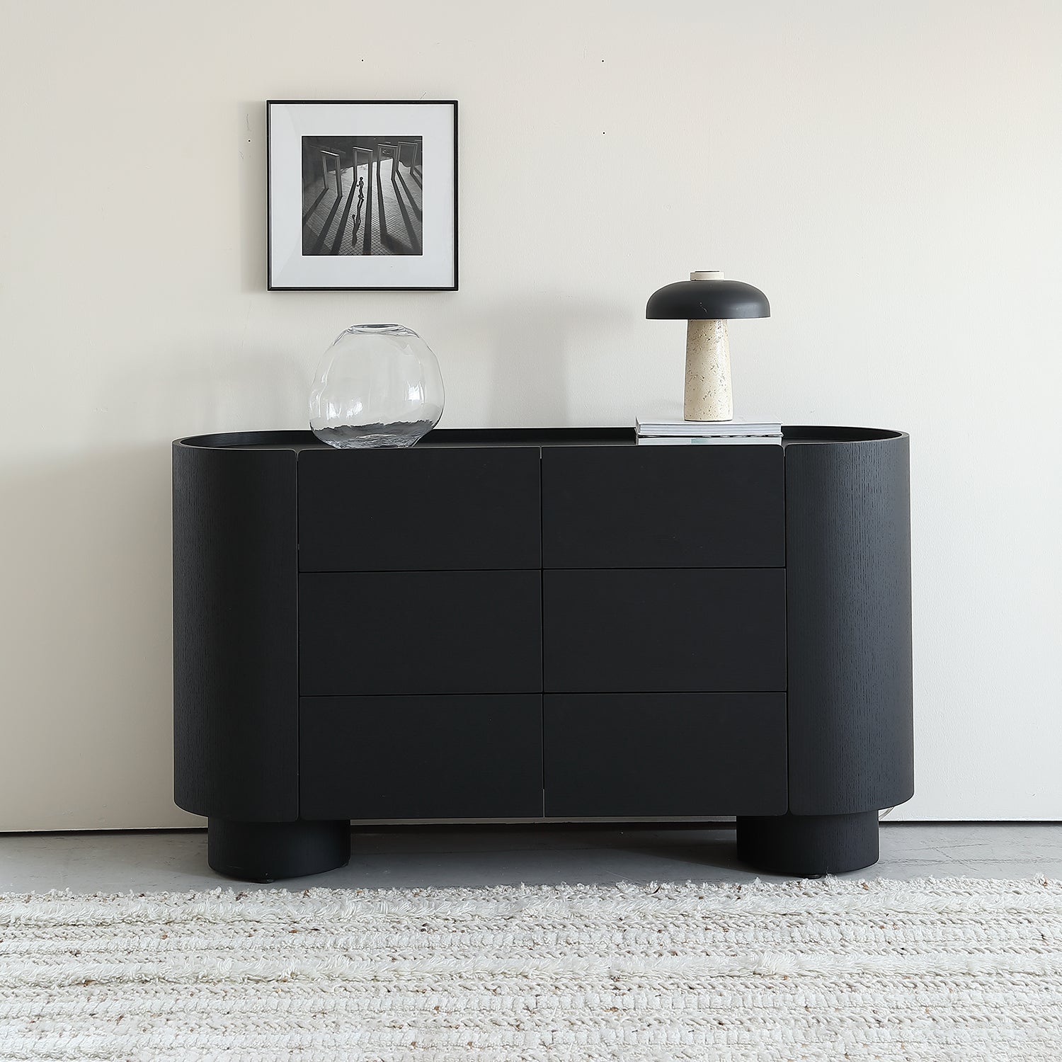 Sculptural black sideboard with rounded corners and minimal drawer fronts, styled as editorial modern furniture.