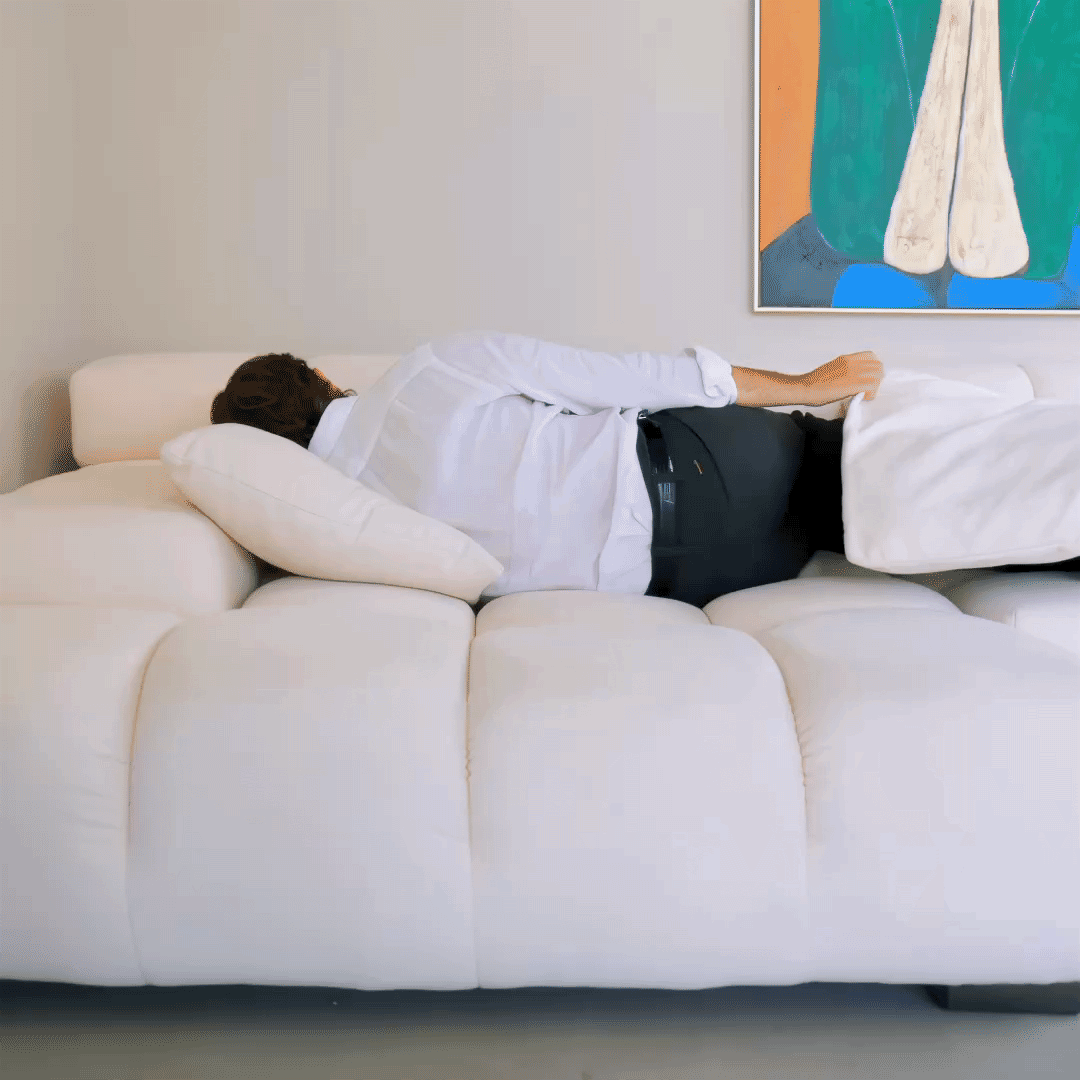 Playfully tossing pillows on Mario Capasa modular sofa, showcasing comfort 